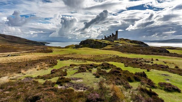 New Scottish golf course with castle ruins visible across open highland terrain and the Moray Firth