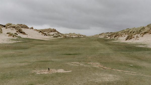 Links golf course fairway with dunes and marram grass under an overcast English coastal sky